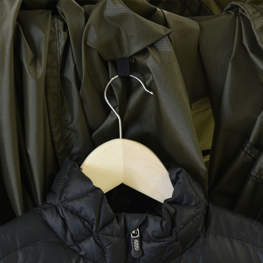 green garment bag with wooden hanger and black jacket
